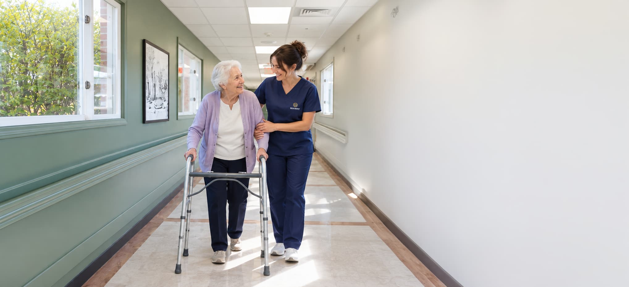A caregiver walking a resident along a sunlit Beaumont corridor